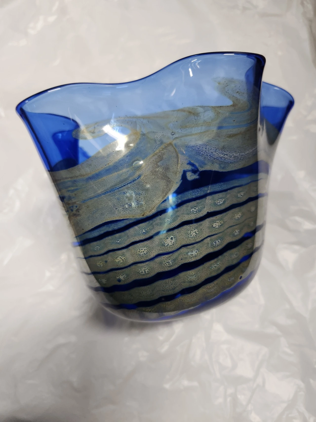 A blue glass bowl with gold and silver stripes.