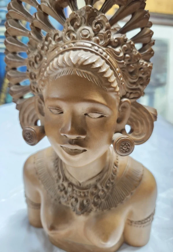 A statue of an indian woman with her head dress up.