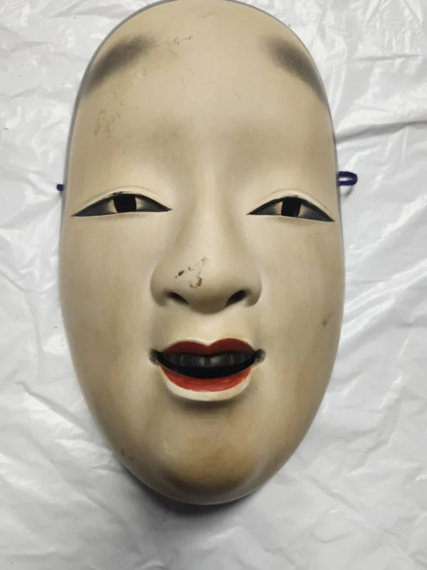 A close up of an asian mask on a white sheet