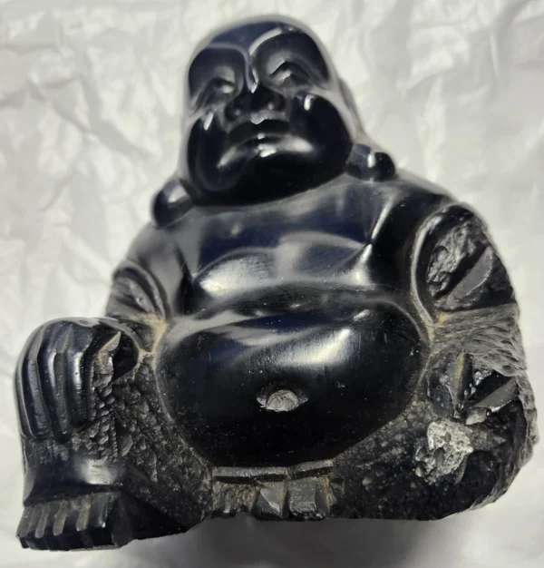 A black buddha statue sitting on top of a white surface.