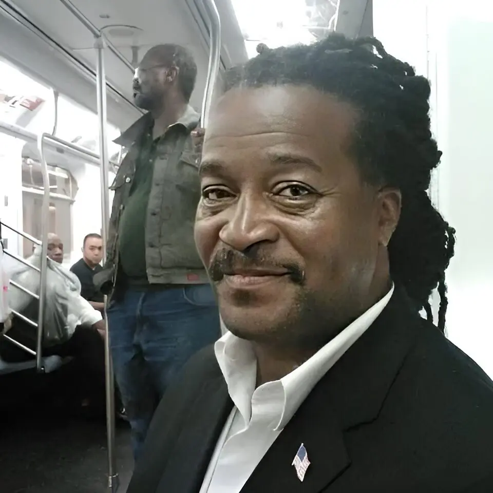 A man with dreadlocks is standing on the subway.