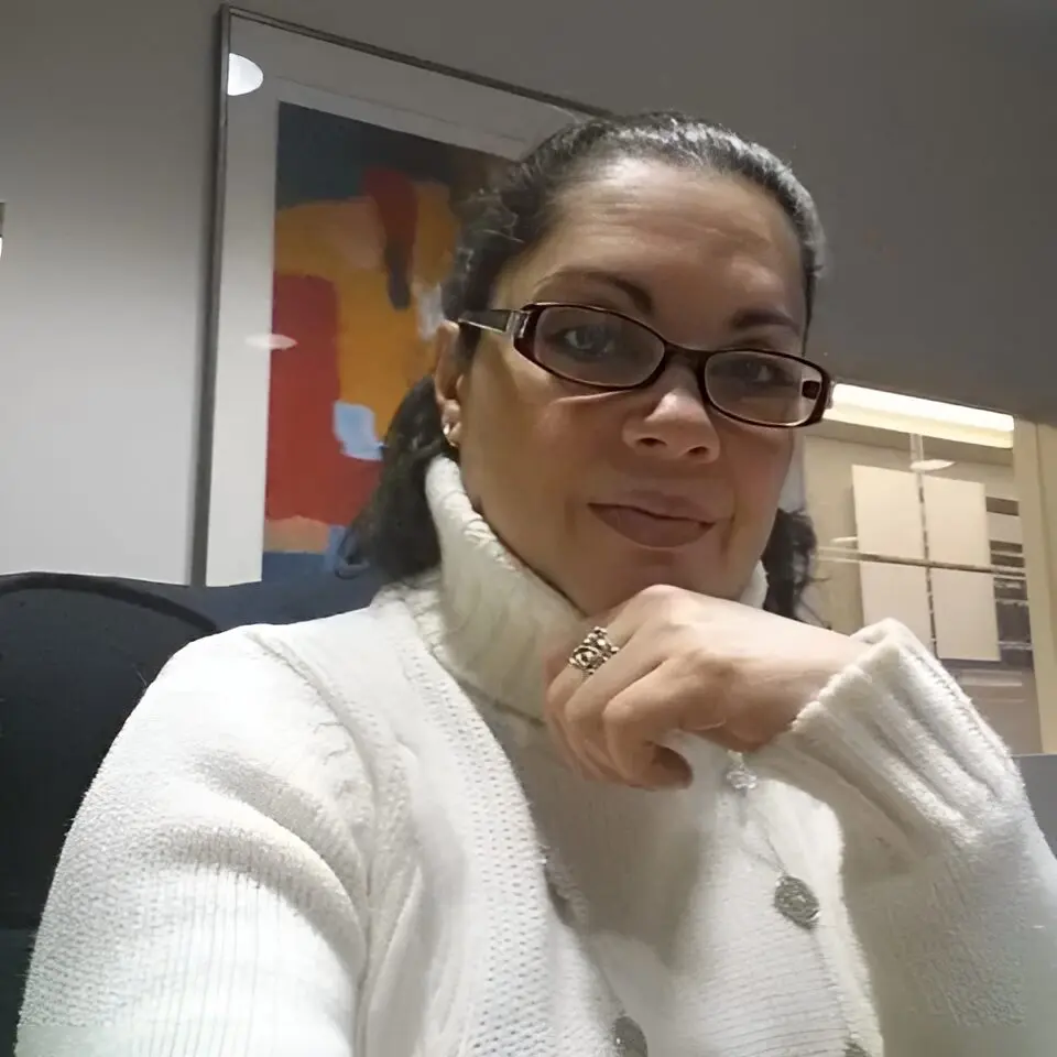 A woman sitting in an office chair wearing glasses.